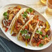 A plate of tacos with Blackbird Foods Original Seitan Shreds, peppers, and onions.