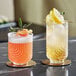 Two Acopa Zelda double old fashioned glasses with orange and yellow drinks and fruit garnishes on a table.