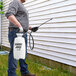 A man using a Chapin Disinfectant Sprayer to spray a house.