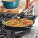 A Vigor enameled carbon steel paella pan of food on a stove.