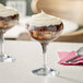 Two Acopa margarita glasses filled with dessert on a table with a pink napkin.