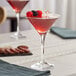 A table with two Acopa Select martini glasses filled with red liquid and berries.