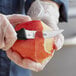 A person in gloves using a Mercer Culinary peeling knife to peel an apple.