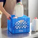 A man putting a milk jug in a blue plastic milk crate with white squares.