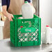 A person holding a white jug of milk in a green Choice Super Crate.