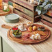 An Acopa acacia wood serving board with food on it on a table.