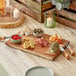 An Acopa live edge acacia wood serving board with food on it on a table.