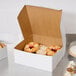 A white 12" x 12" bakery box filled with cupcakes with frosting and sprinkles.