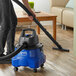 A person using a Lavex Pro wet/dry vacuum to clean a wood floor.