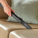 A person using a Lavex Pro wet/dry vacuum to clean a couch.
