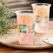 Two New Roots compostable plastic cups with pink drinks and lemon slices on a table.