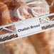 A Clear clip-on label holder on a rack with a label that says "Chalah Bread"