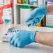 A person in a Showa blue biodegradable nitrile glove using a knife to cut something on a counter.