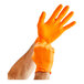 A pair of hands wearing Lavex Pro orange nitrile gloves.