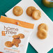 A yellow bag of Homefree Gluten-Free Organic Mini Ginger Snap Cookies on a white surface with cookies spilling out.