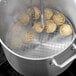 A Choice chrome-plated steel steamer rack with dumplings cooking in a pot.