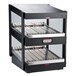 A black Nemco countertop double shelf food warmer on a counter in a bakery display.
