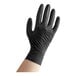 A hand wearing a black Noble NexGen biodegradable nitrile glove.
