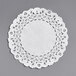 A 4" white Normandy lace doily on a gray surface.