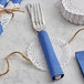 A table set with blue napkins and silverware with a 4" Normandy Lace doily on each plate.