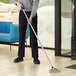 A person using a Lavex 8" scraper blade to clean the floor.
