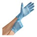 A person's hands wearing blue Noble Products disposable gloves.