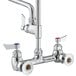 A chrome Waterloo wall-mounted pre-rinse faucet with two faucets and two handles.