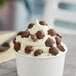 A white cup of mini milk chocolate caramel turtles.