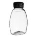 A clear plastic Classic Queenline honey bottle with a black plastic flip top lid.