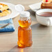 An 8 oz. PET bear bottle of honey with a white cap on a table.