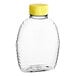 A clear plastic Classic Queenline honey bottle with a yellow cap.