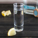 A customizable Arcoroc cordial glass filled with liquid and a lemon slice on a table.