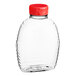 A clear plastic Classic Queenline honey bottle with a red lid.