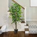 A 6' artificial ficus tree in a black metal pot sits on a stair next to a carpet.