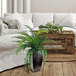 An LCG Sales artificial river fern plant in a copper metal planter on a wood table in a living room.
