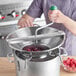 A person using the Garde stainless steel rotary food mill to make raspberry jam.
