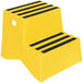 A yellow Vestil step stool with black stripes.