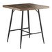 A Lancaster Table & Seating bar height table with a wooden butcher block top and black metal legs.