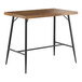 A Lancaster Table & Seating Mid-Century bar height table with a butcher block top and black legs.