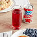 A glass of Ocean Spray cranberry juice cocktail next to a can of cranberry juice on a table with food.