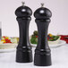 Two black Chef Specialties Windsor ebony finish pepper mills on a table.