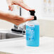 A hand using a SC Johnson Professional Azure foaming hand soap dispenser.
