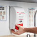 A hand using a SC Johnson Professional white and red foaming hand sanitizer dispenser.