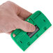 A hand holding a green Unger ProTrim 10 glass scraper.