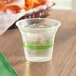 A clear World Centric plastic cup filled with ice water on a table.