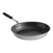 A Vollrath stainless steel frying pan with a black and silver design and black handle.