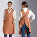 Two women wearing Acopa Ashville smock bib aprons with different colors.