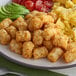A plate of tater tots and scrambled eggs with a fork.