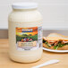 A white jar of Heavy Duty Mayonnaise on a table next to a sandwich.