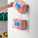 A hand using a Noble Products Double Box Acrylic Wall-Mount Glove Dispenser to grab a box of gloves from a wall.